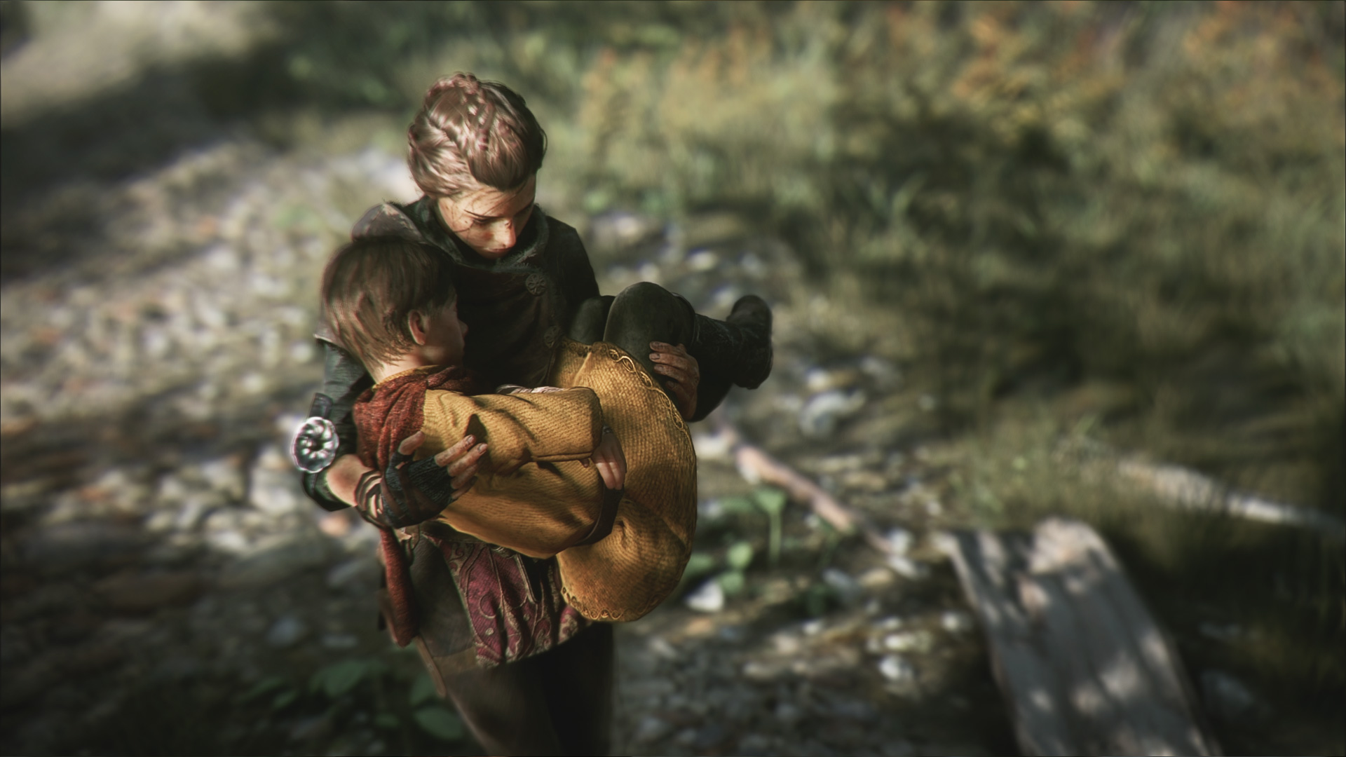 Amicia holds Hugo close on a woodland path.