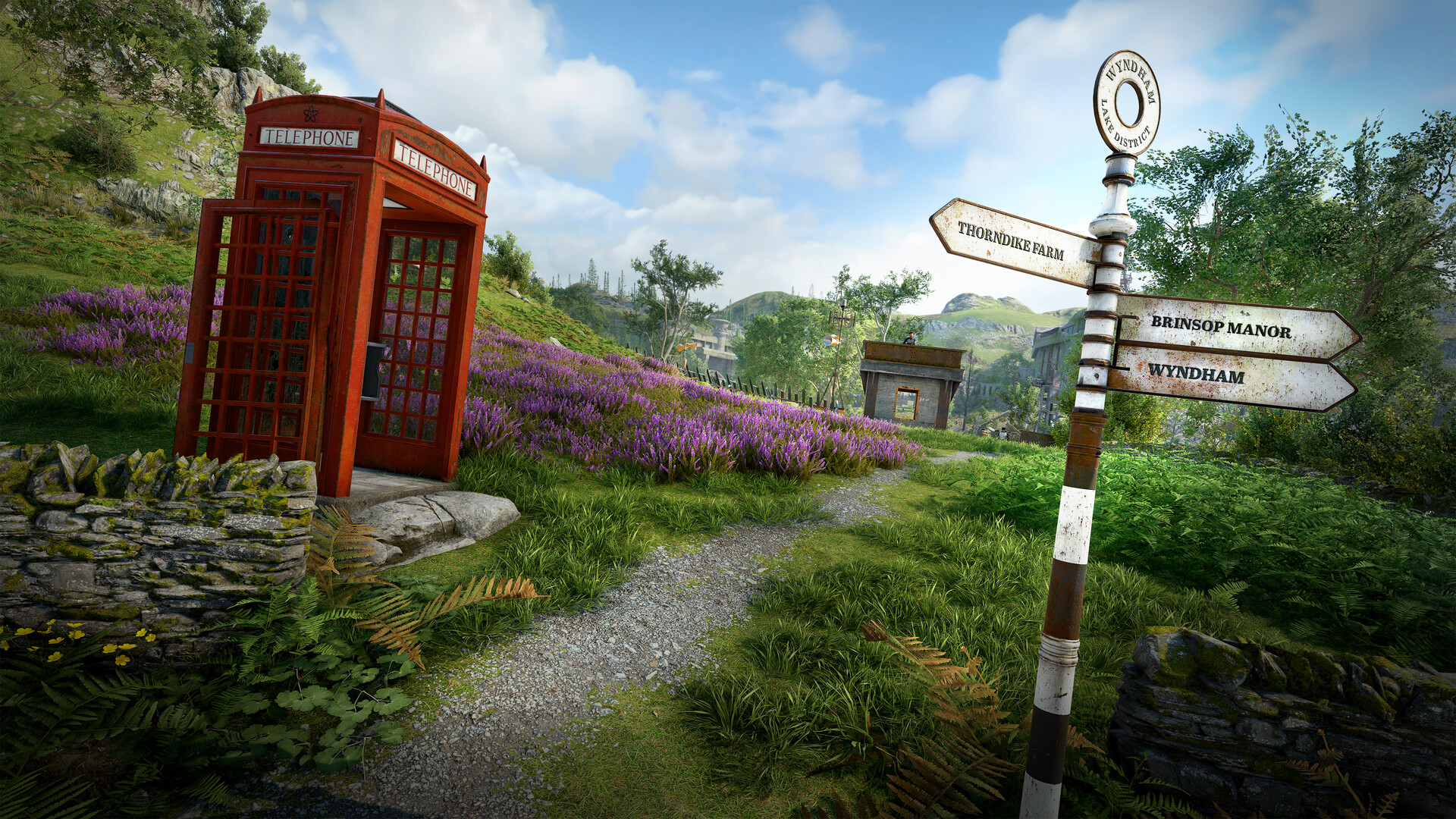 A red telephone box and signpost stand beside a path through the Wyndham Lake District.