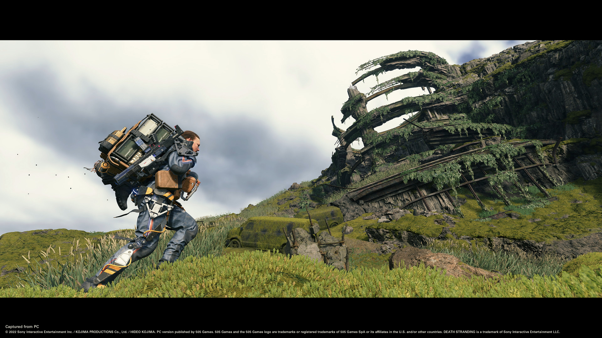 Sam carries cargo up a grassy mountain slope.