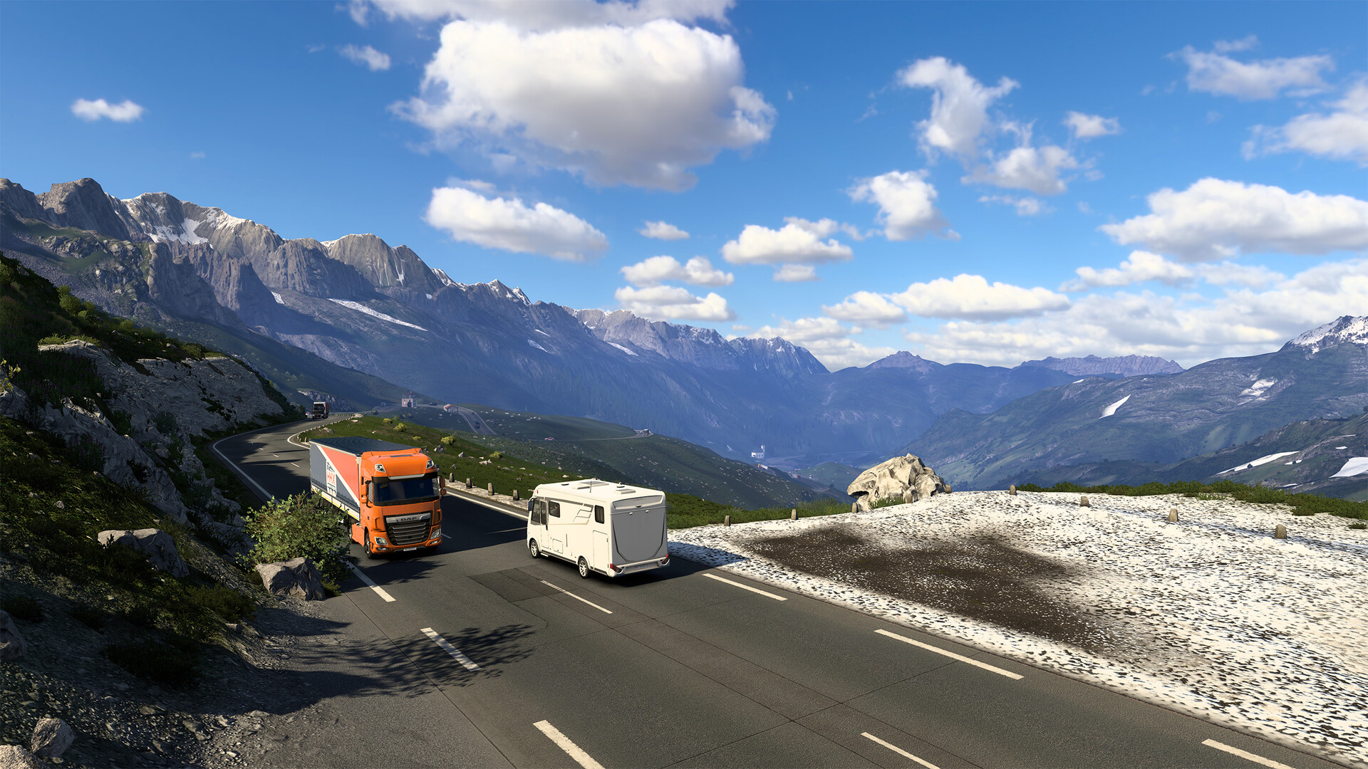 An orange lorry drives along a mountain road beside a motorhome.