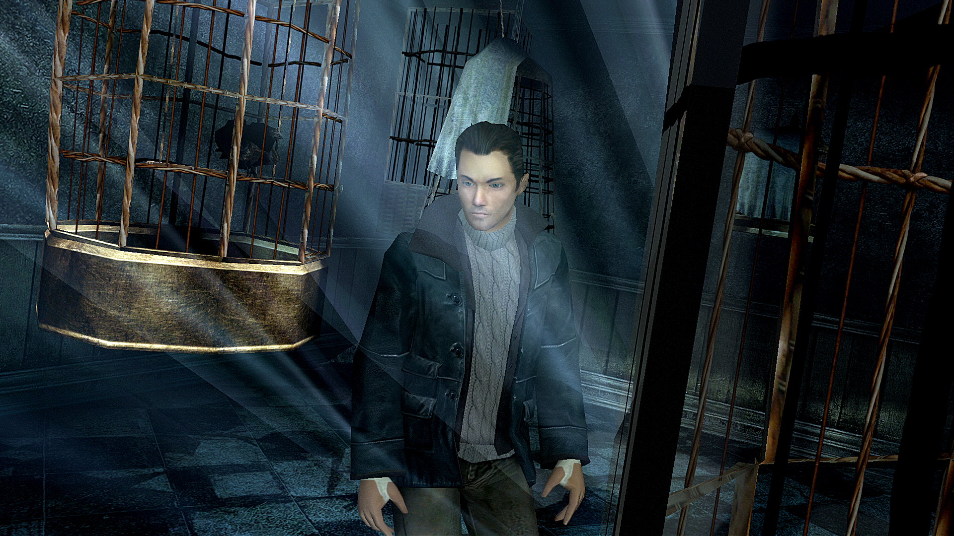 A man stands beside hanging cages in a dim room.