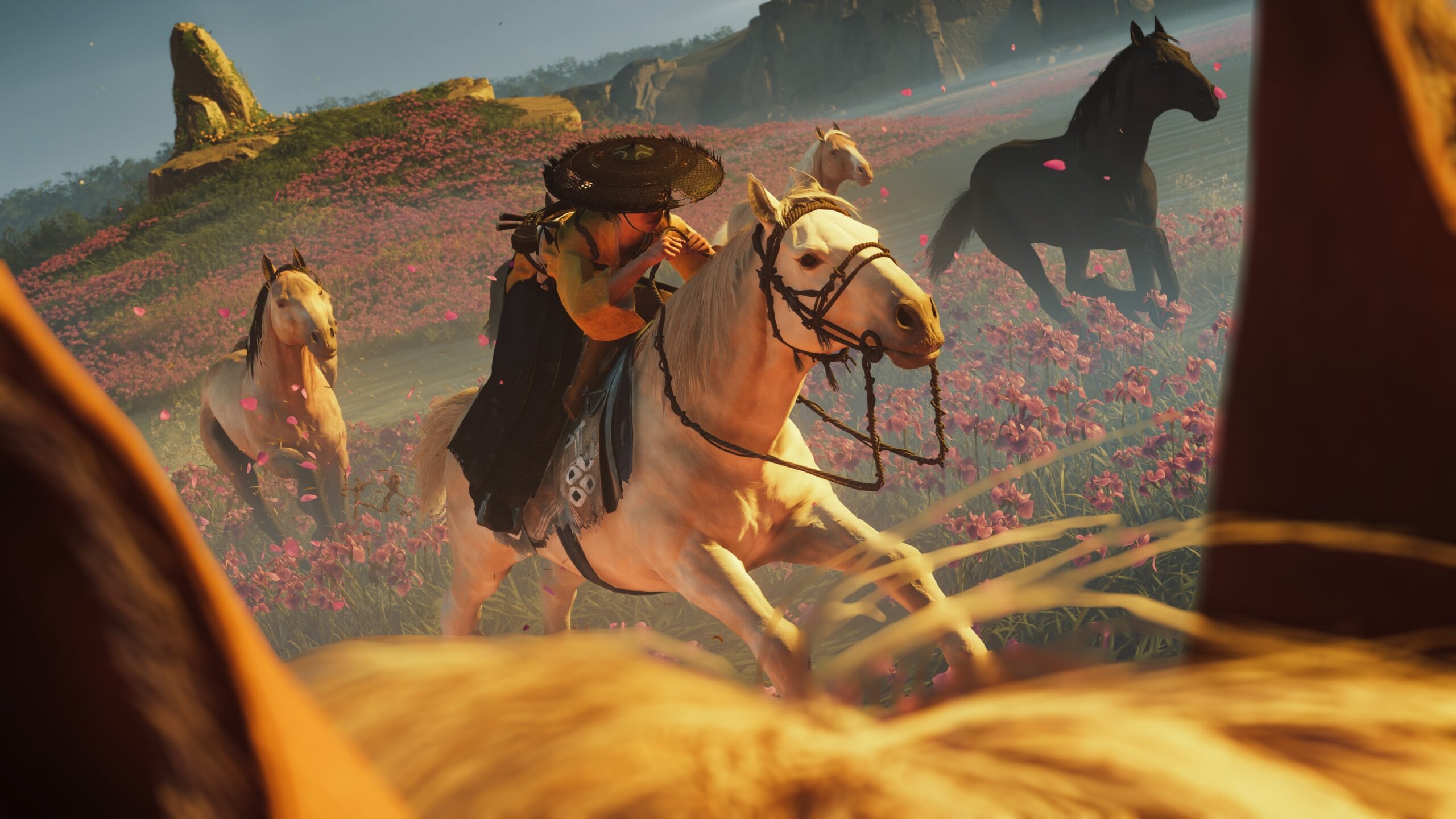 Atsu rides a white horse through a field of pink flowers beneath Mount Yōtei.