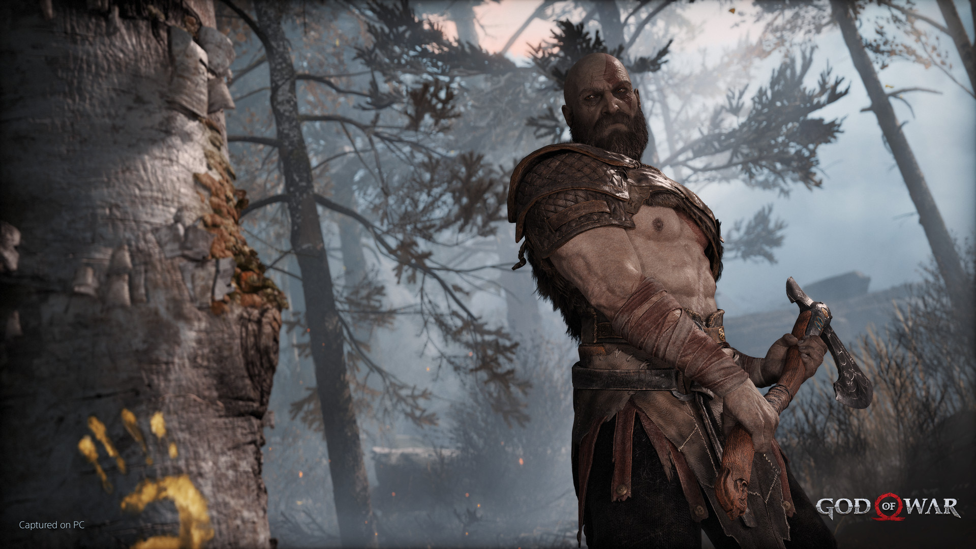 Kratos holds the Leviathan Axe in a wooded landscape.