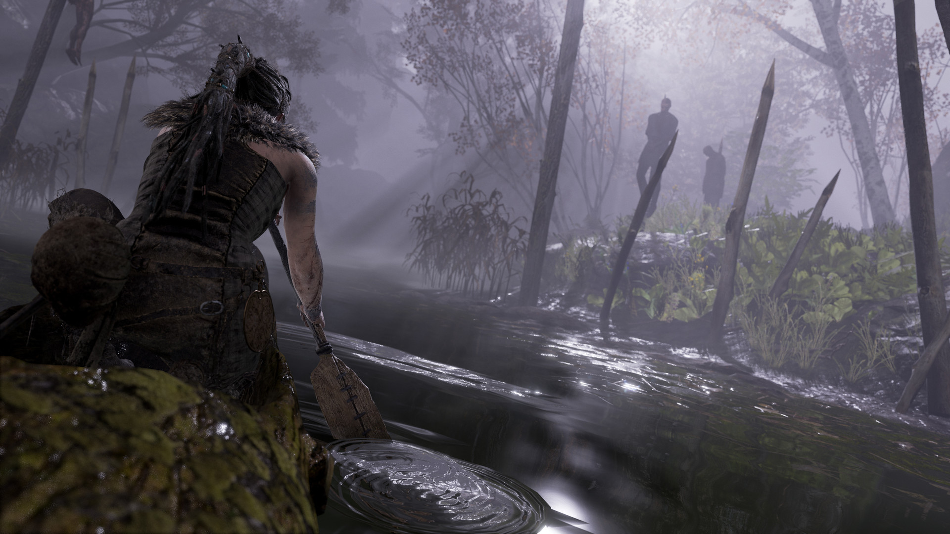 Senua looks through a misty forest toward hanging figures.