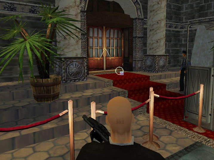 Agent 47 approaches a guarded doorway inside an ornate building.