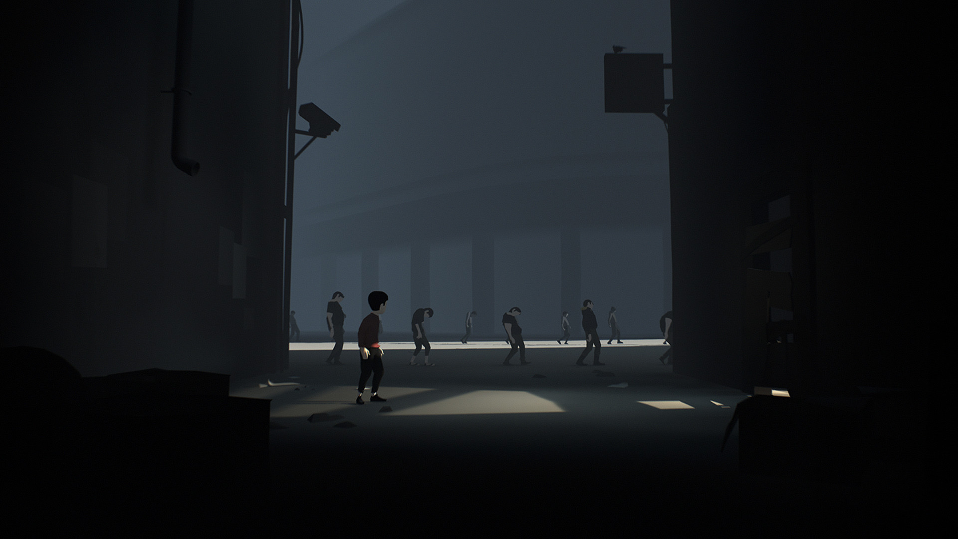 The boy stands near a group of figures in a dim facility.