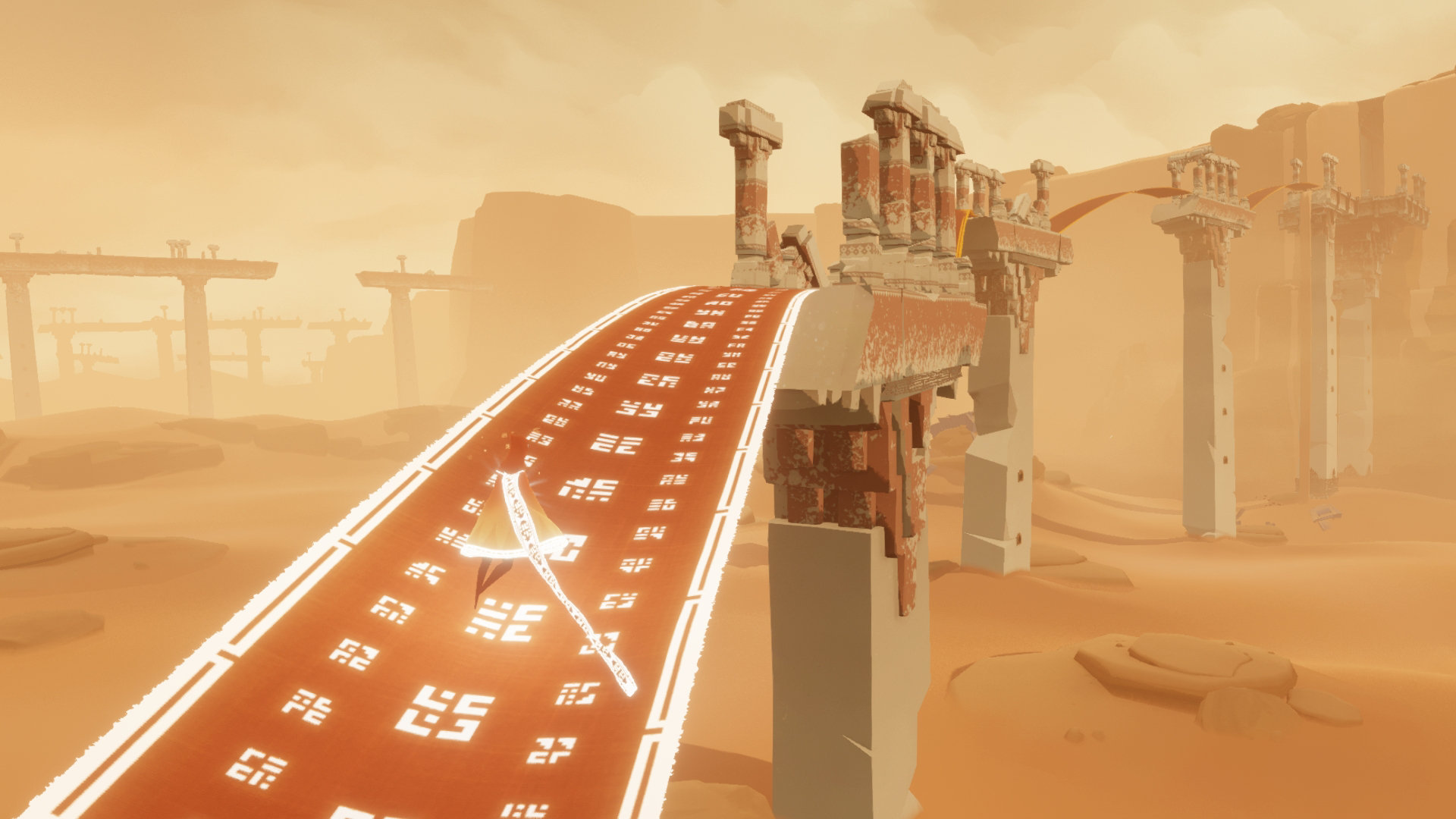 A patterned ribbon bridge spans weathered ruins in the desert.