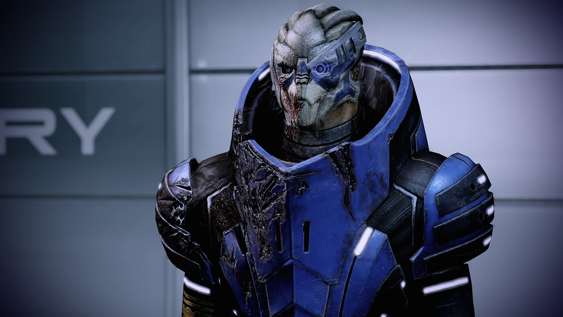Garrus stands in armour inside a ship or facility.