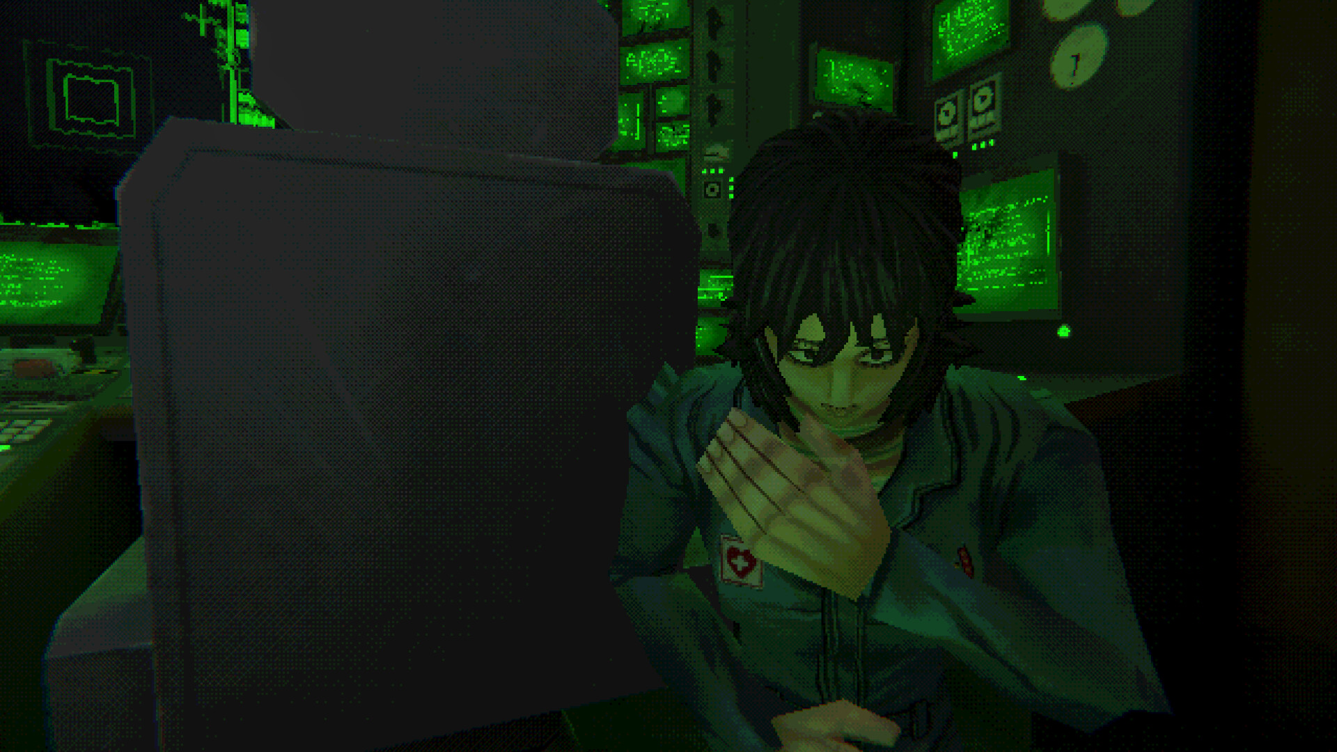 A crew member sits beside a monitor in a green-lit room.