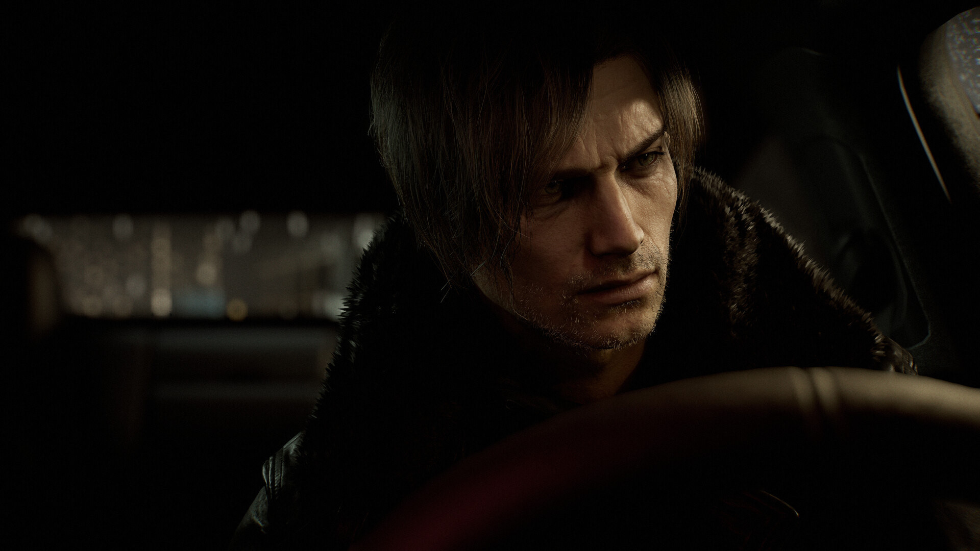 Leon looks ahead from a dimly lit vehicle.