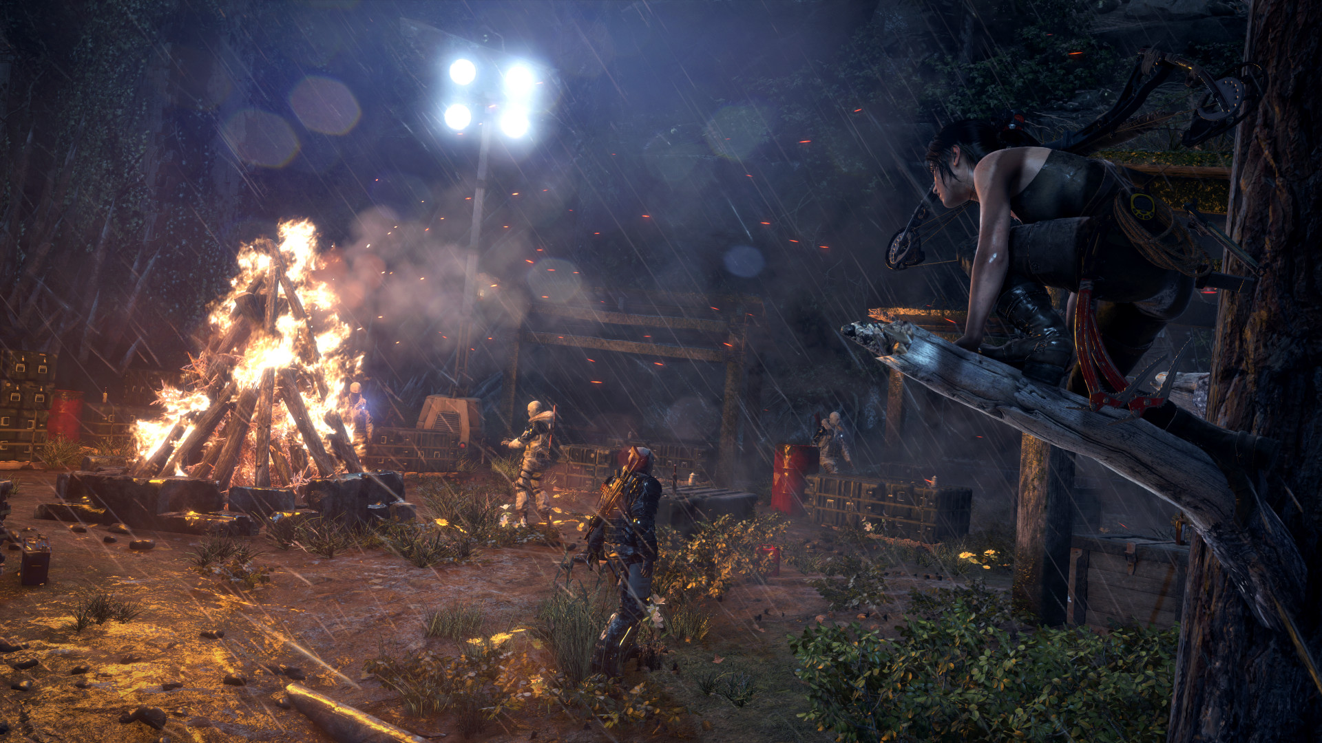 Lara watches a camp from an elevated position at night.