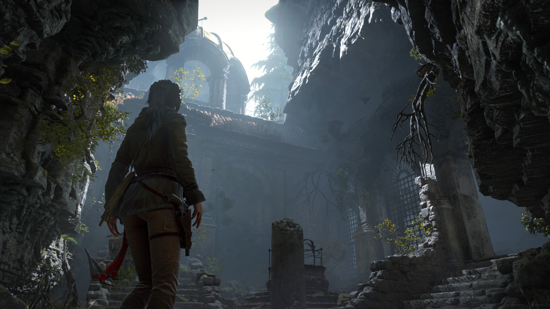 Lara enters a ruined structure beneath a rocky opening.