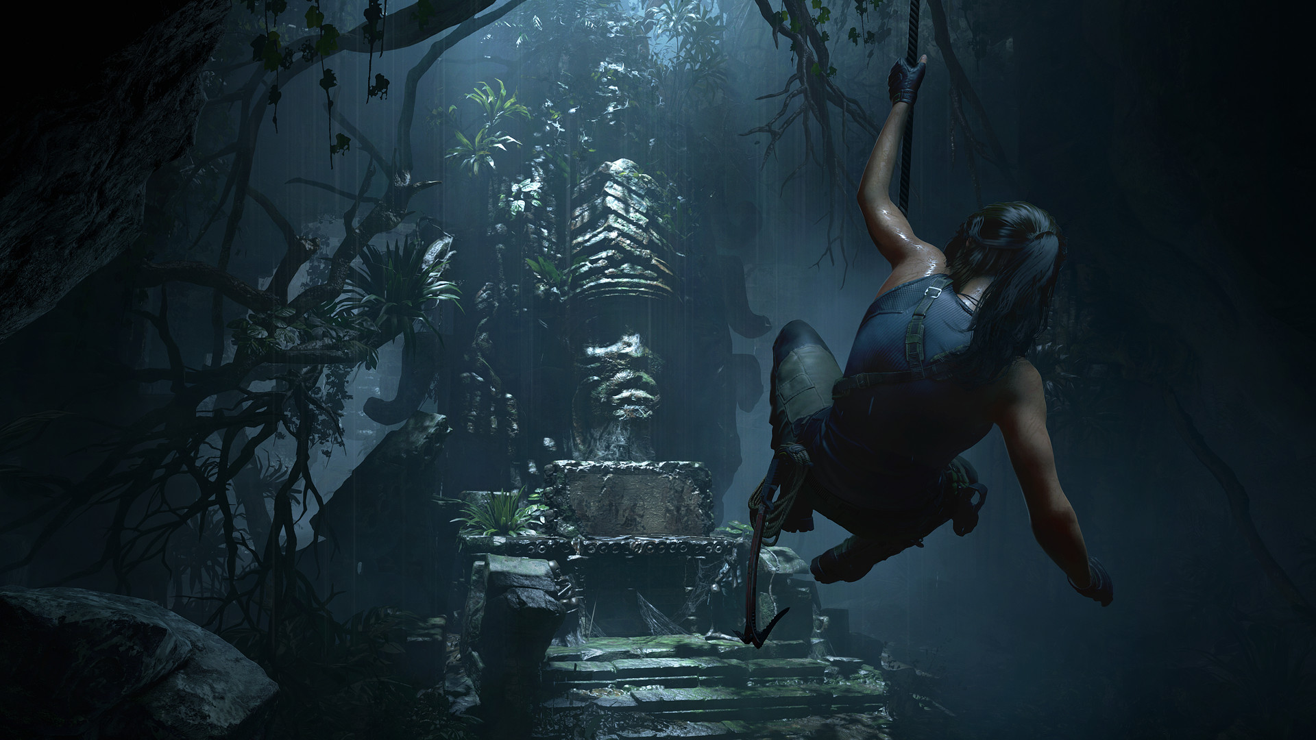 Lara swings toward a carved structure in a jungle ruin.