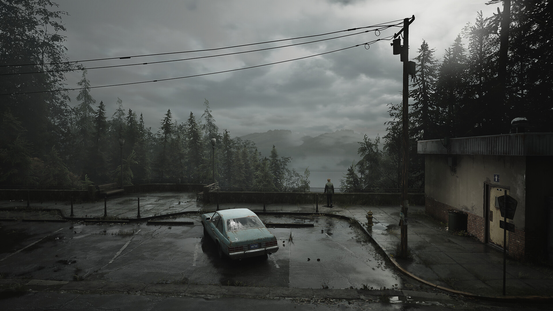 A parked car sits beside a misty road into Silent Hill.