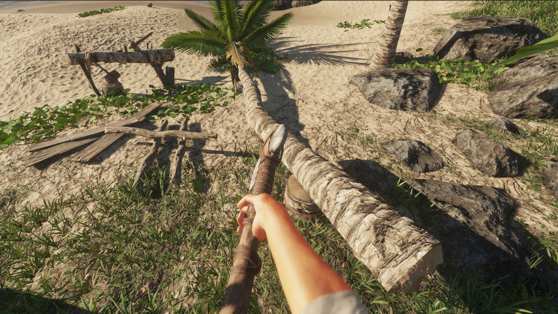 A survivor chops a log on a sandy island.