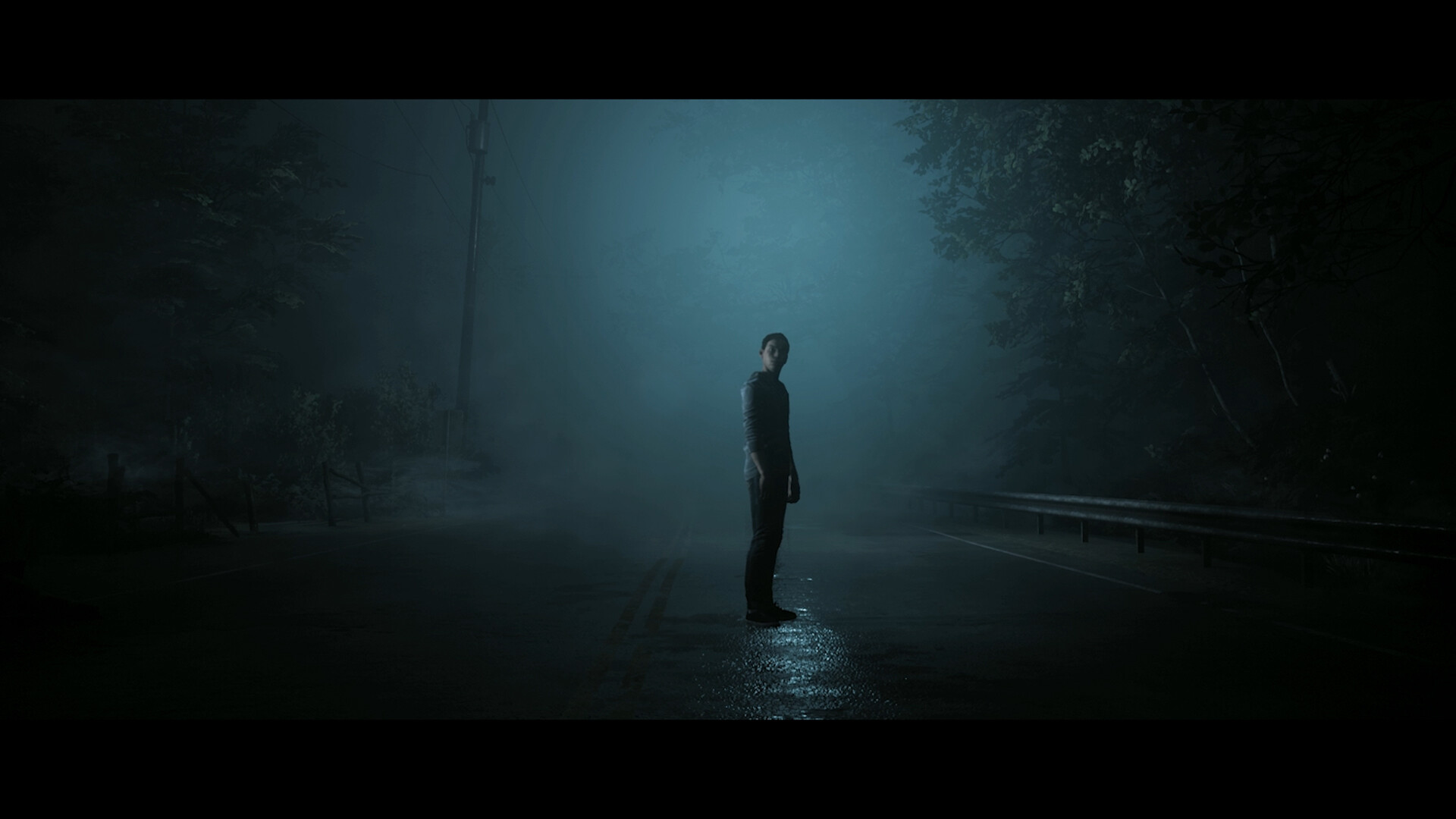 A lone person stands on a fog-covered road.