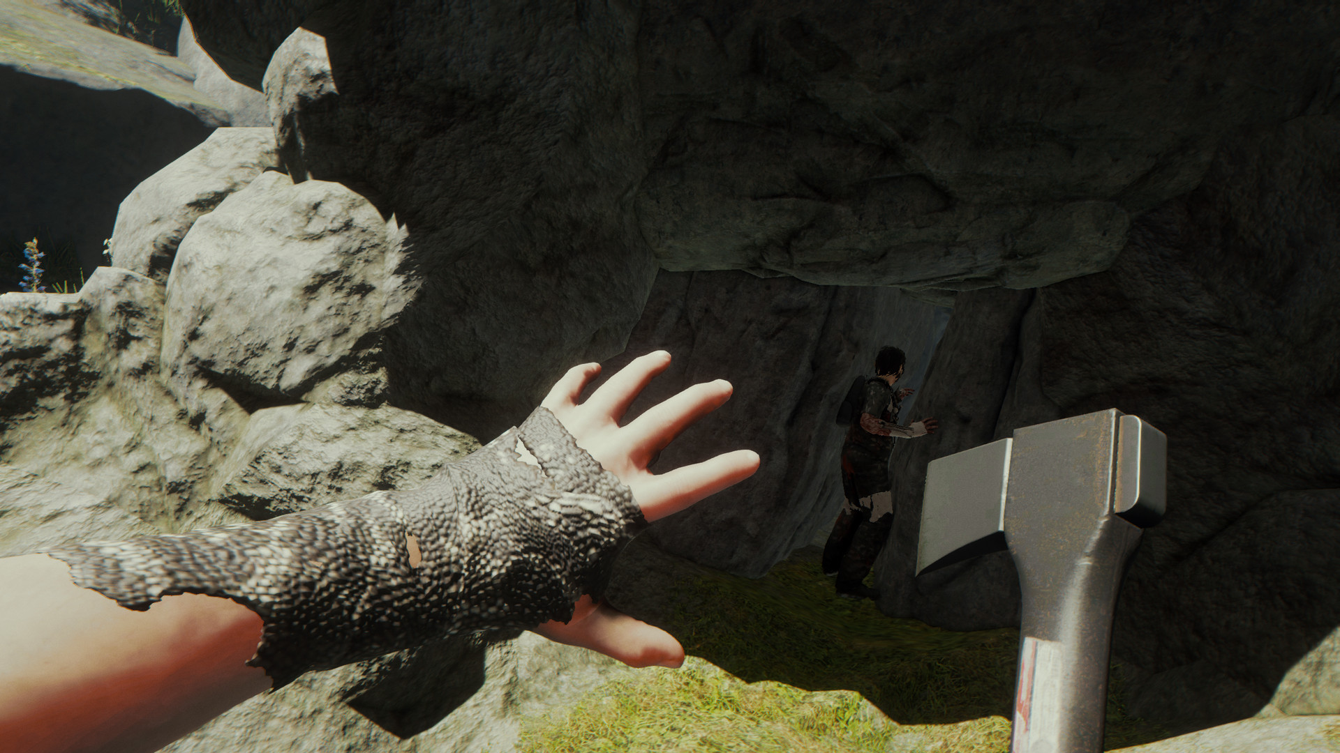 A survivor carrying an axe approaches a cave entrance.
