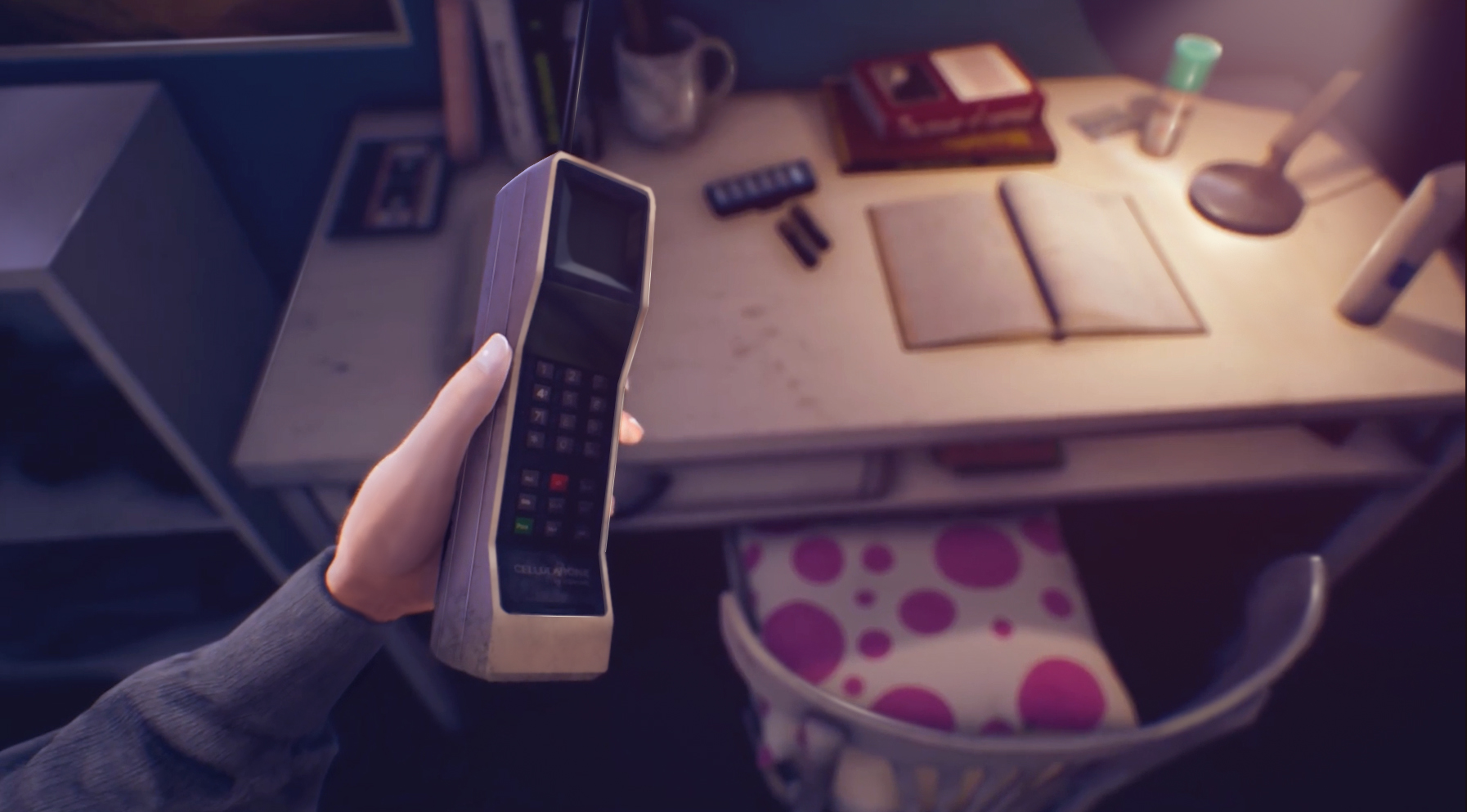 A hand holds a radio telephone above a desk.