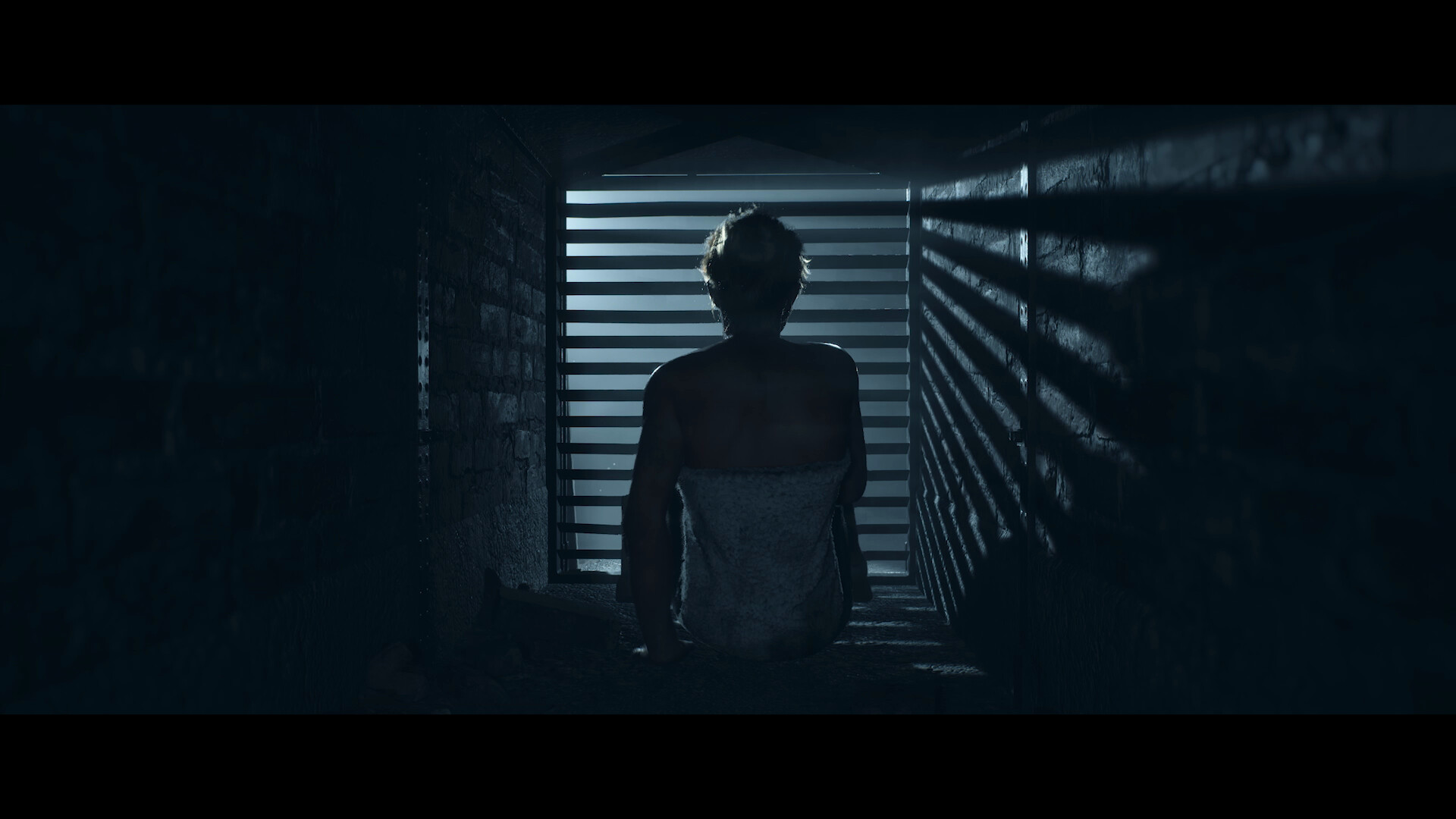 A person approaches a shuttered opening in the dark.