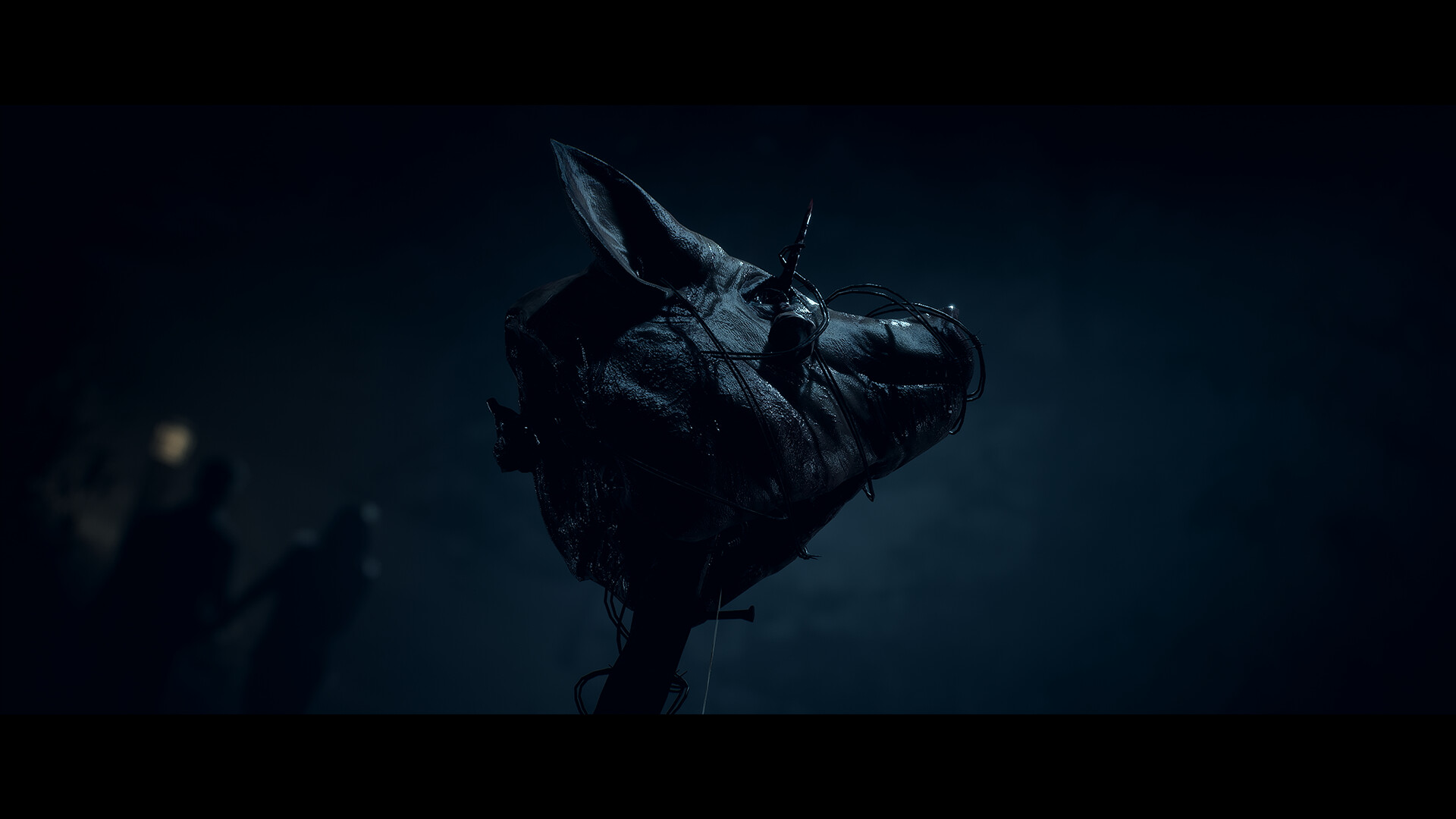 A carved animal head emerges from darkness.